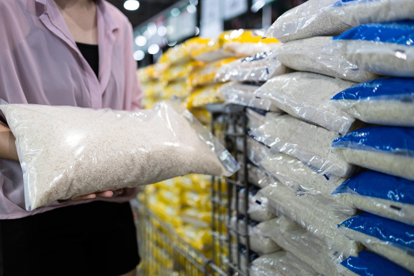 A female in a grocery store holding a bag of white rice