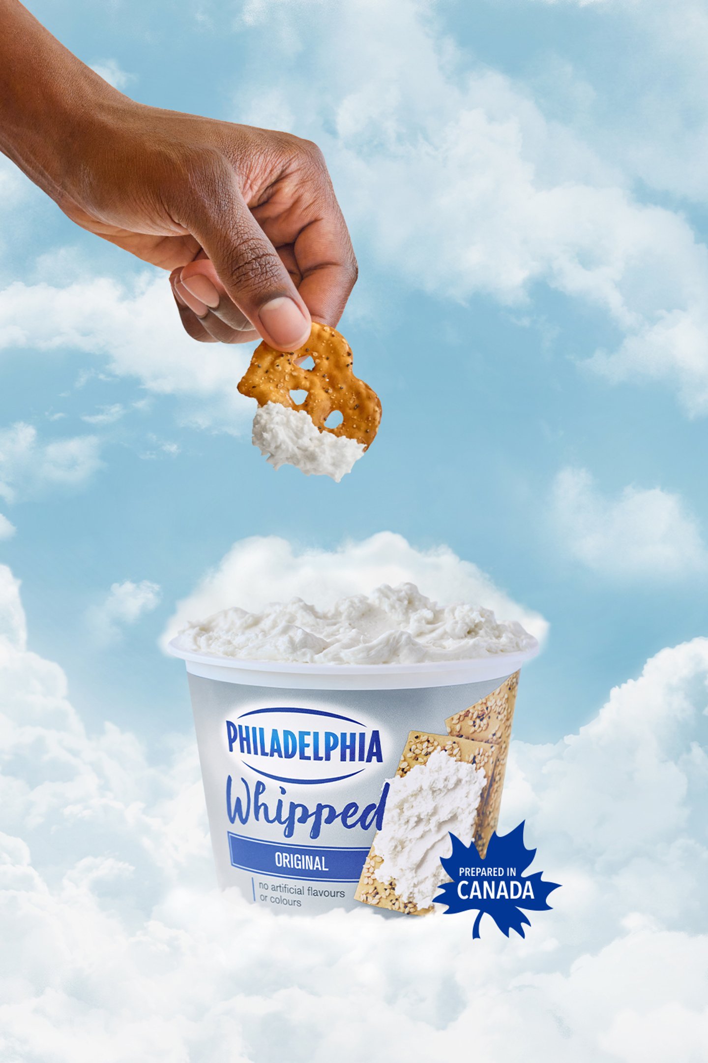 A hand coming down from the clouds to dip a pretzel into a tub of whipped cream cheese