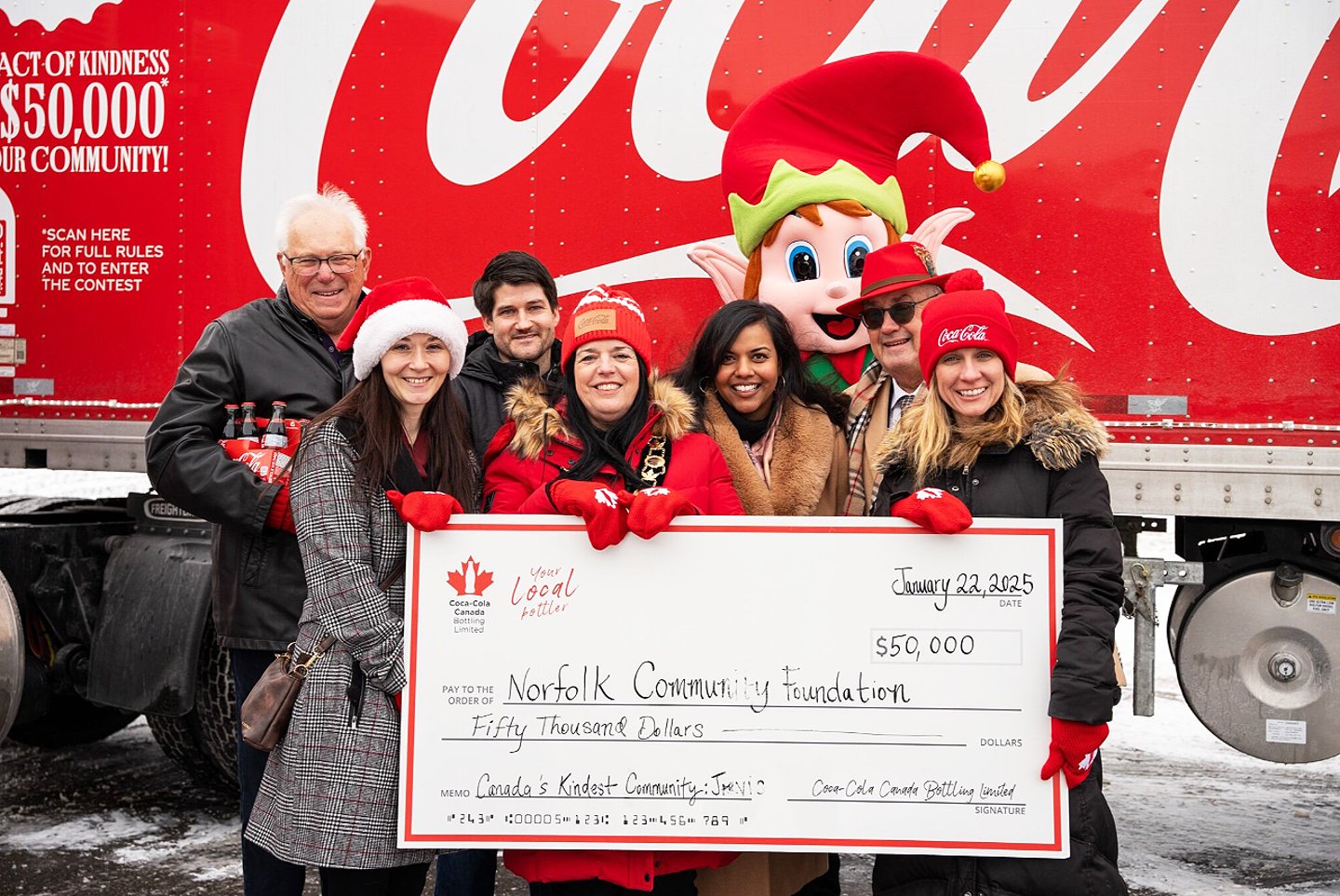 People holding a large cheque standing in front of a Coca Cola truck