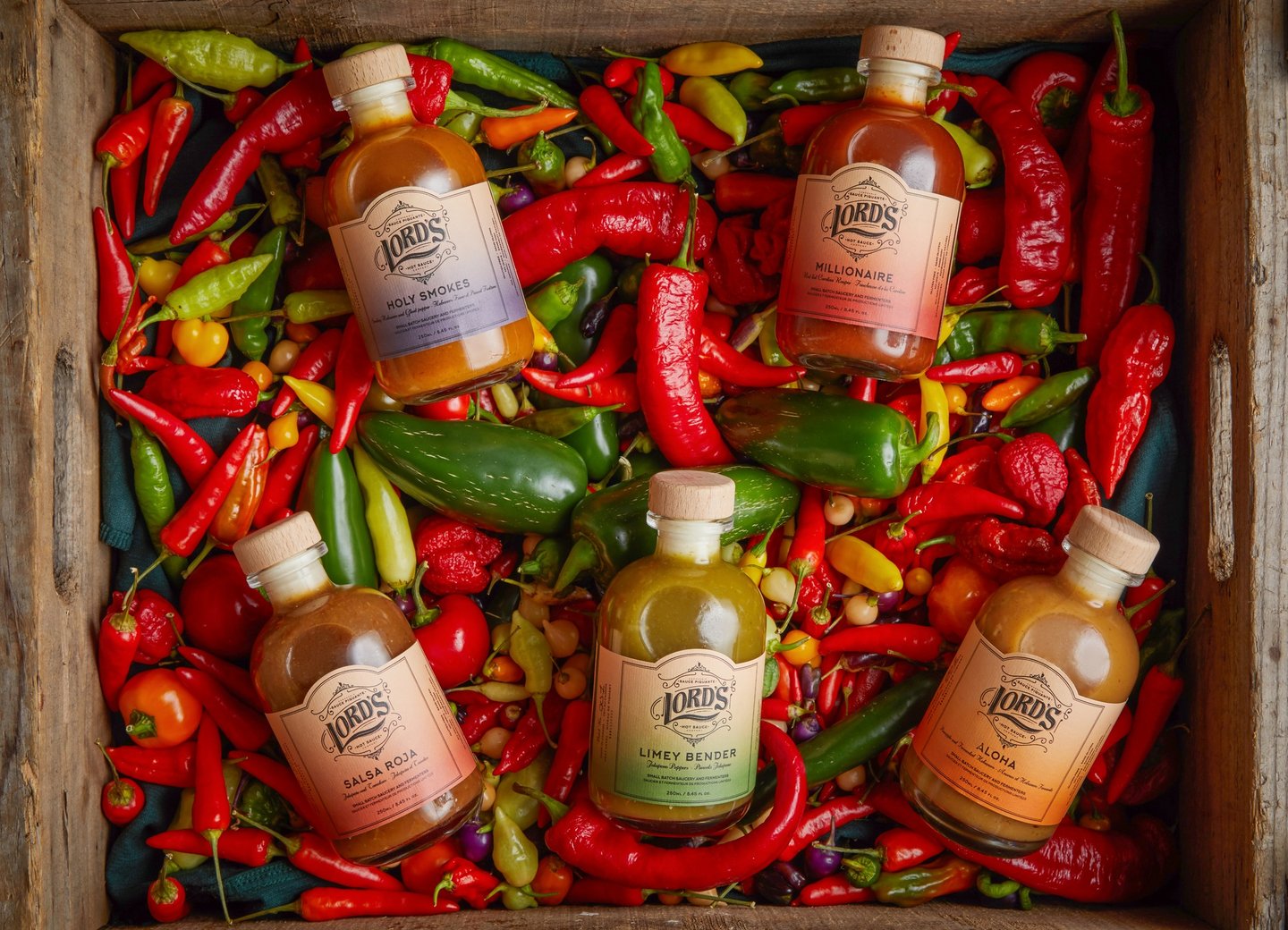 Bottles of Lord's Hot Sauce on a bed of peppers