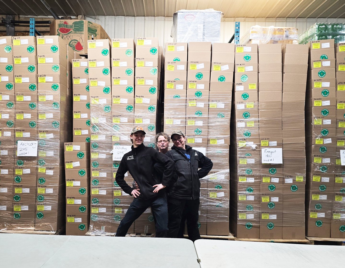 Three store employees standing in front of packed boxes of food