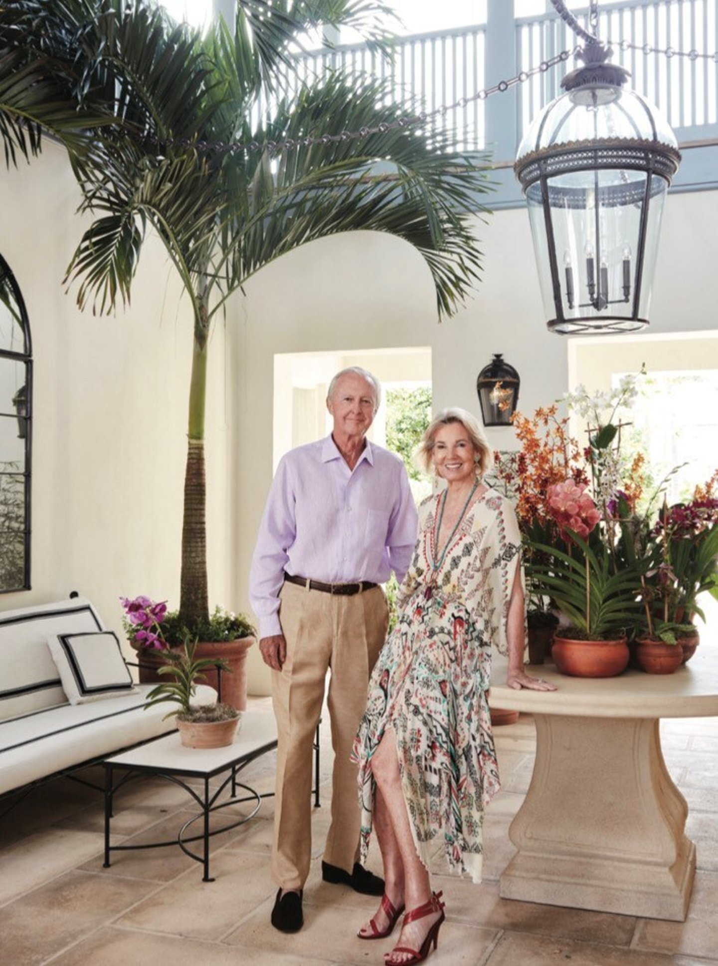 Galen Weston Sr. and Hilary Weston side by side in a foyer with a large palm plant in the background
