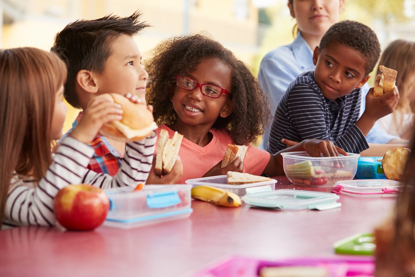 Young school kids eating lunch talking at a table together