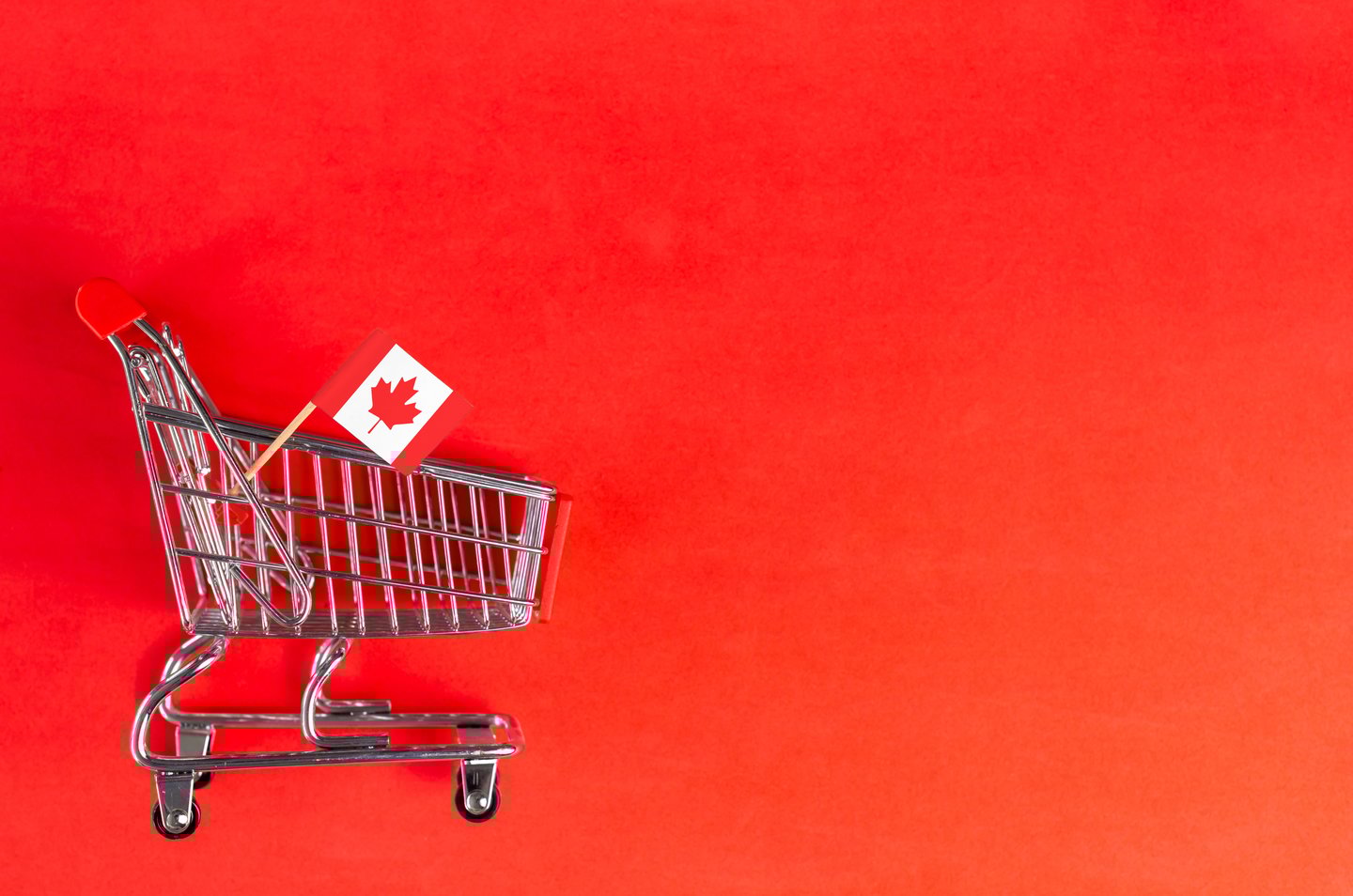 Shopping cart and Canada flag on red background. Shopping online or eCommerce, delivery service store