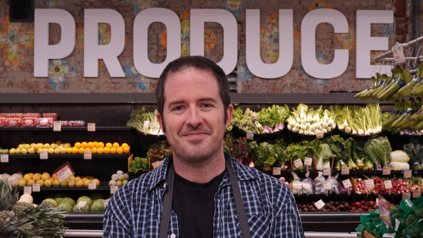 Grocer Digs Dorfman standing in the produce section of his store