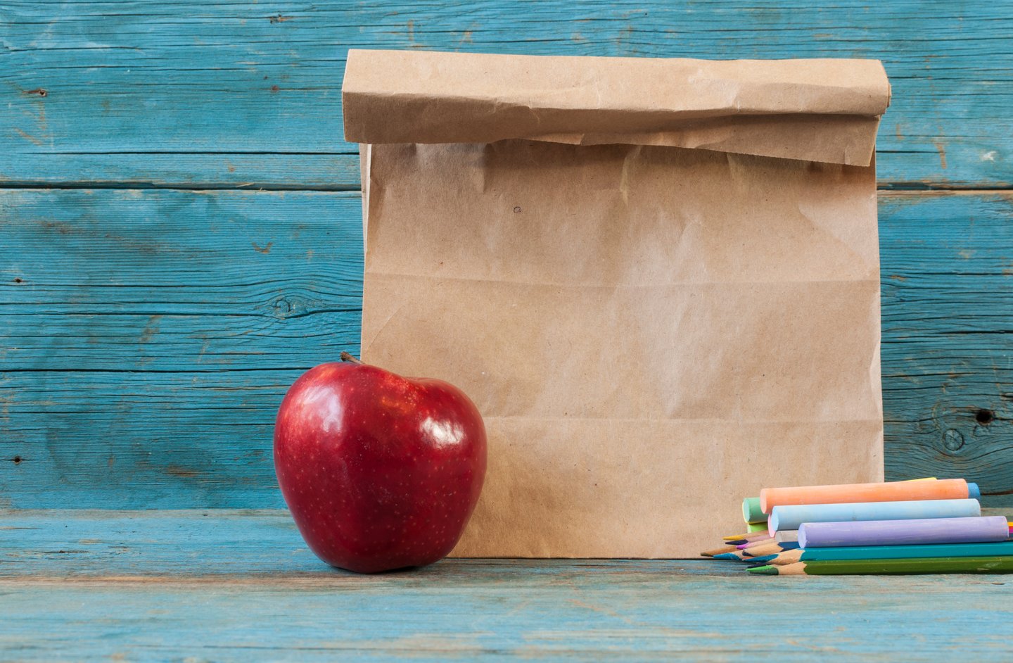 School lunch in a brown bag with an apple and chalk 