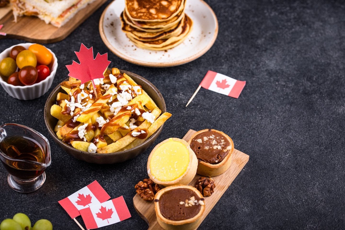 A spread of Canadian foods poutine, pancakes, tarts and maple syrup