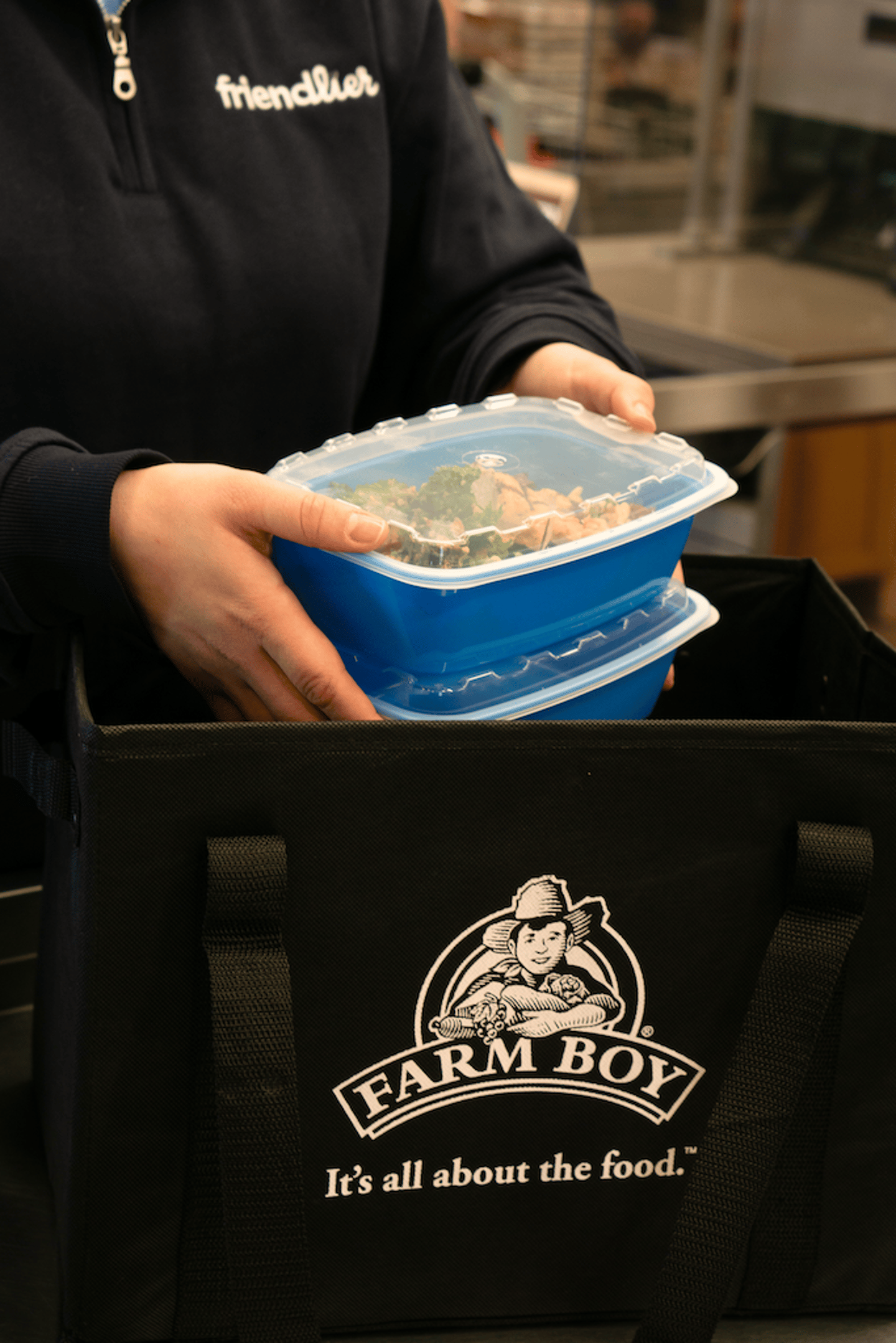 Friendlier reusable containers being placed into a Farm Boy black grocery bag.