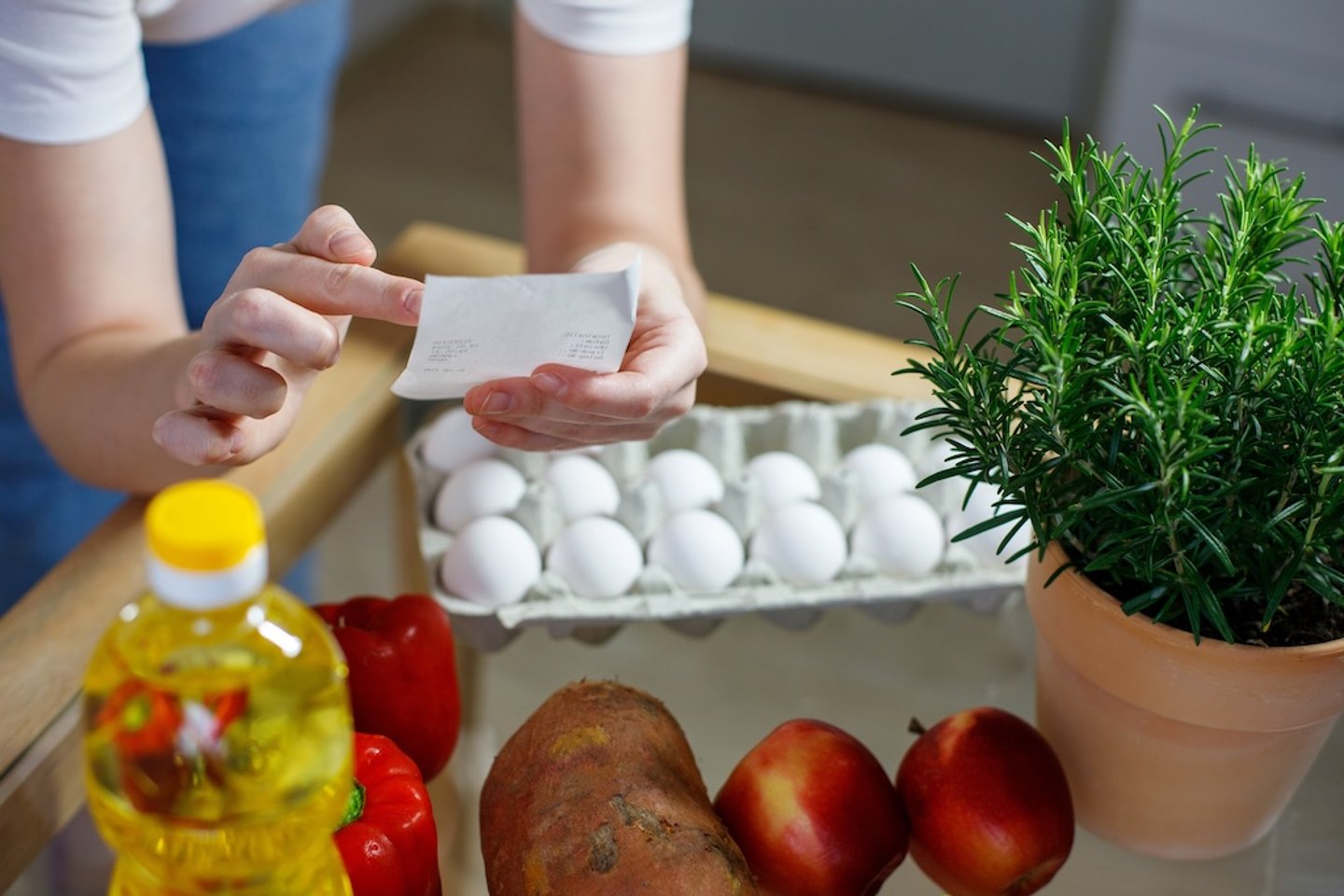 hands checking a grocery receipt above food on a counter