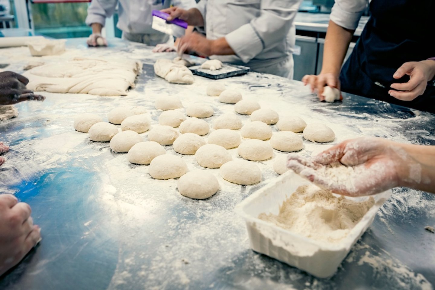 Hands rolling dough in flour