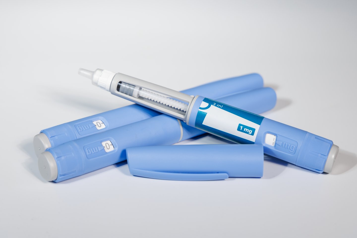 GLP-1 semaglutide injection pens with pills and measuring tape over white background illustrating health and prevention