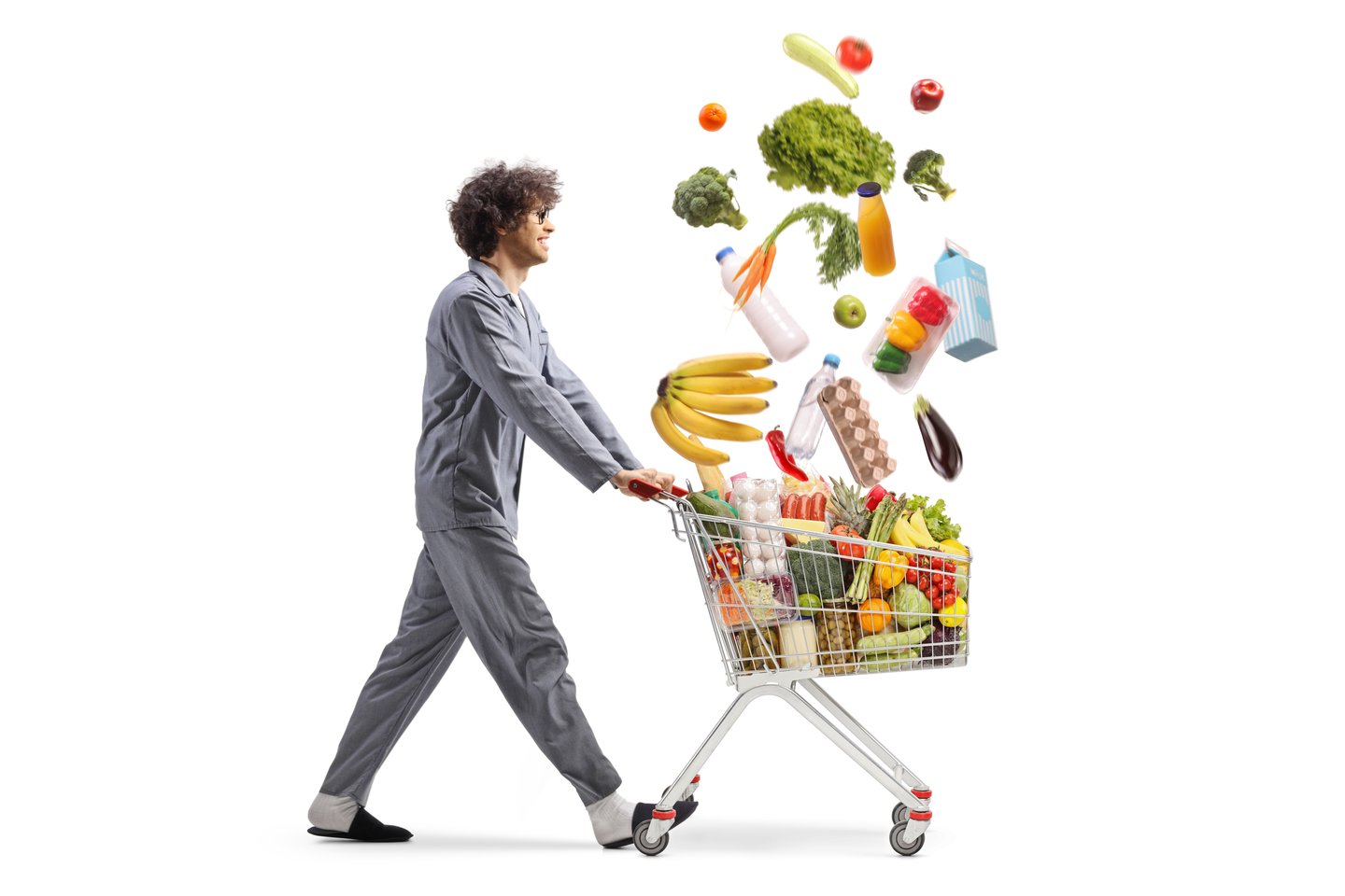 Man in pajamas pushing a shopping cart with falling groceries isolated on white background
