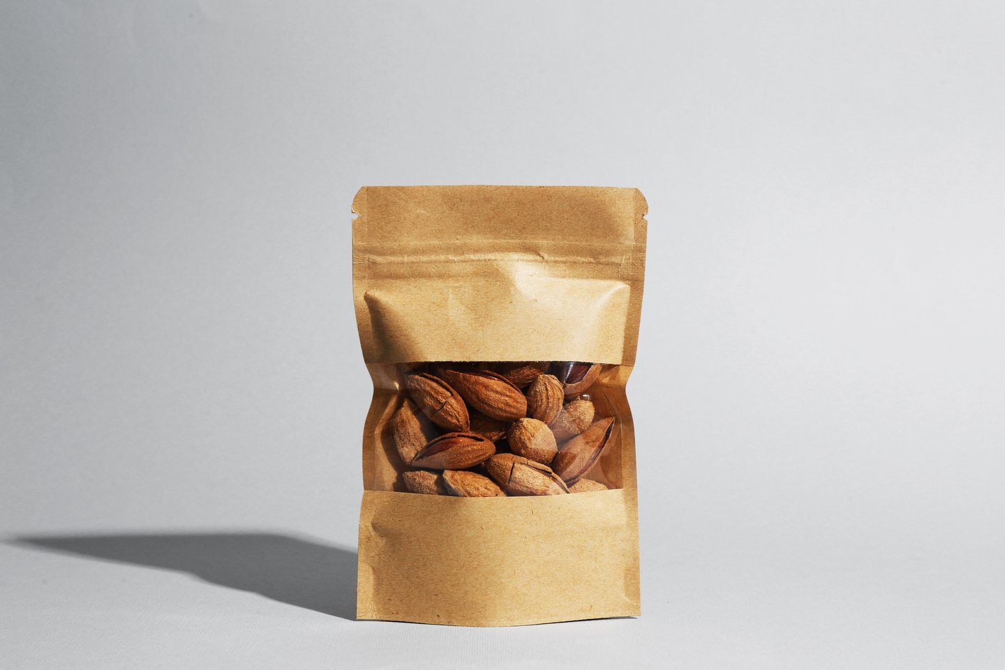 Stand-up pouch with almond nuts on grey background