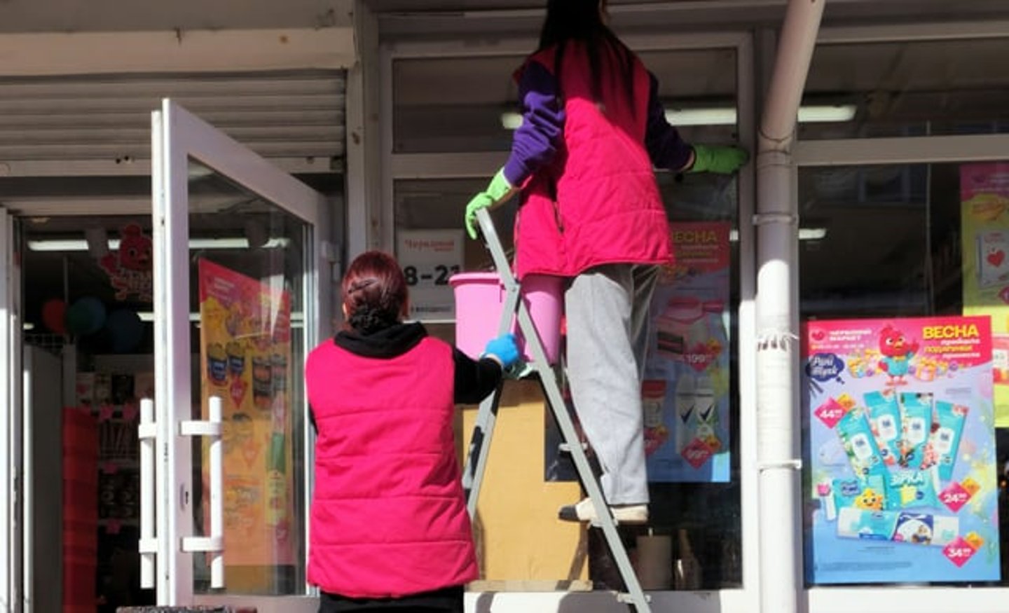 store staff cleaning outside windows