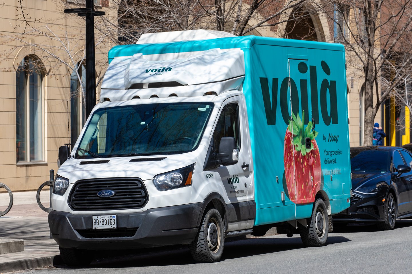 A grocery home delivery truck on a downtown city street for the Canadian Sobeys grocery store chain under the Voila brand