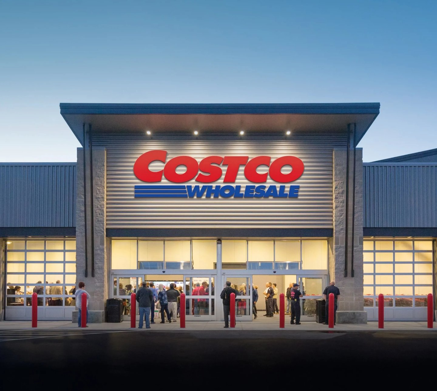 Outside shot of a Costco at night with people in the entrance way