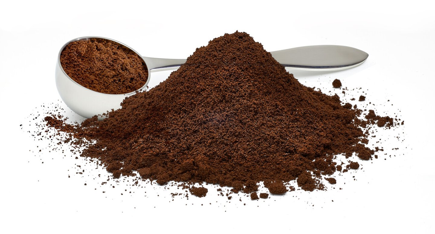 Ground coffee pile with metallic measuring scoop isolated on white background; Shutterstock ID 1386556535
