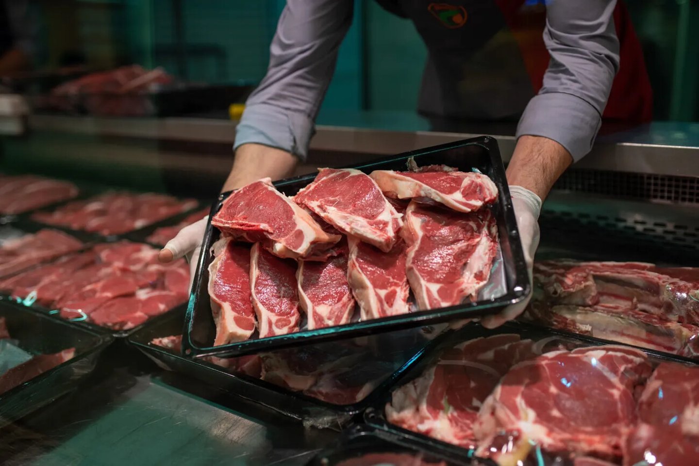 Closeup of butcher's hands holding meat piece in shop; Shutterstock ID 2450875827