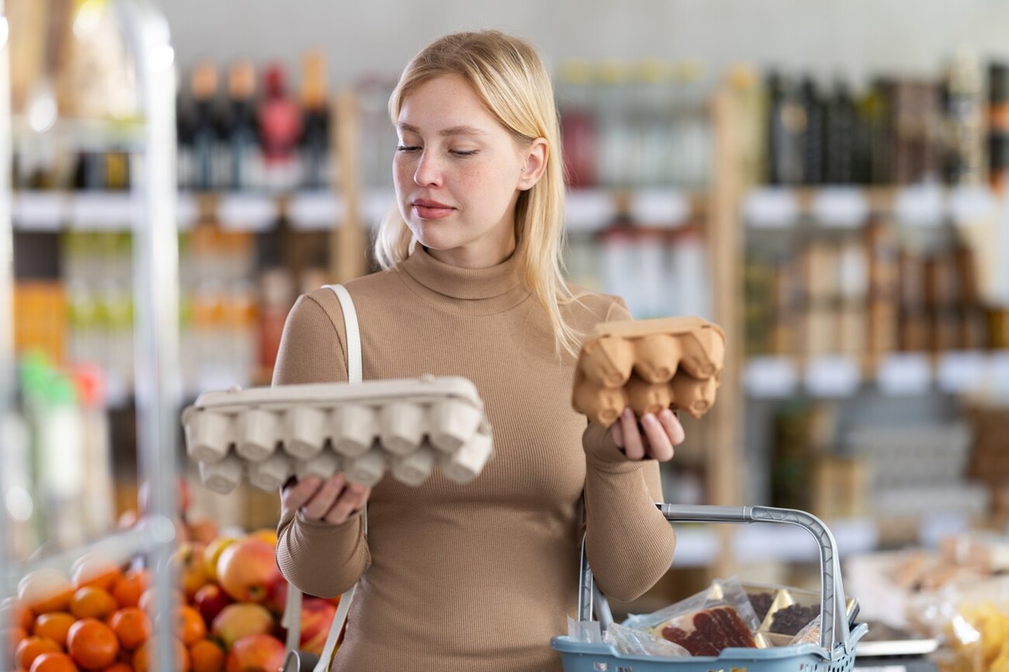 Girl buyer choosing compare varieties eggs, doubt and think before buying. Client look package of eggs, inspect product and examines contents of package; Shutterstock ID 2577981909