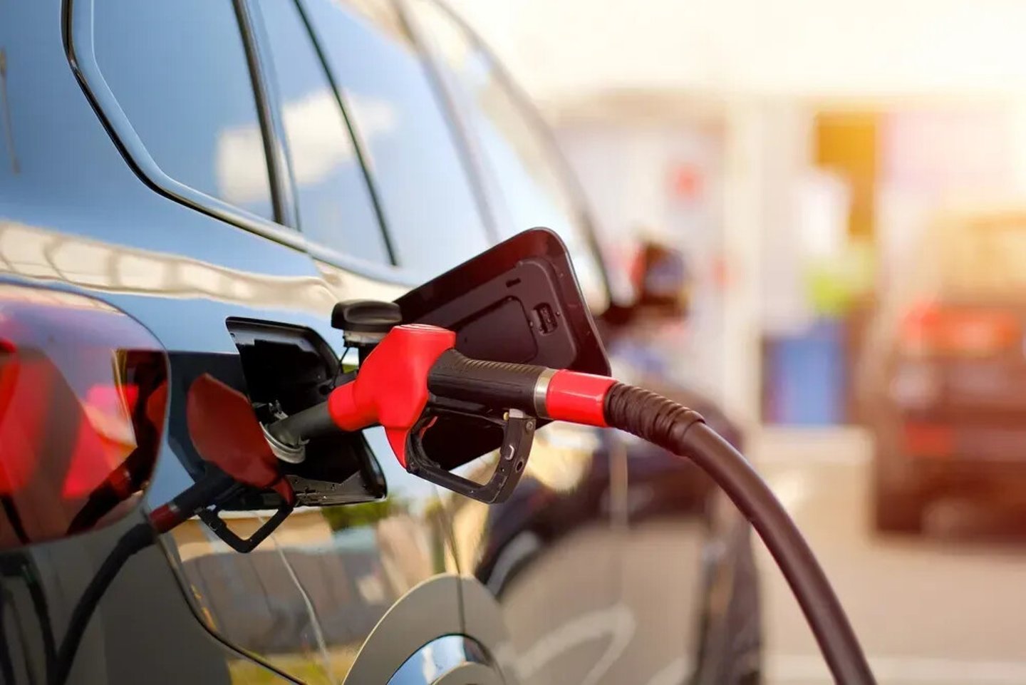 Close-Up of Fuel Nozzle Refueling Black Car at Gas Station During Sunset; Shutterstock ID 2644445047