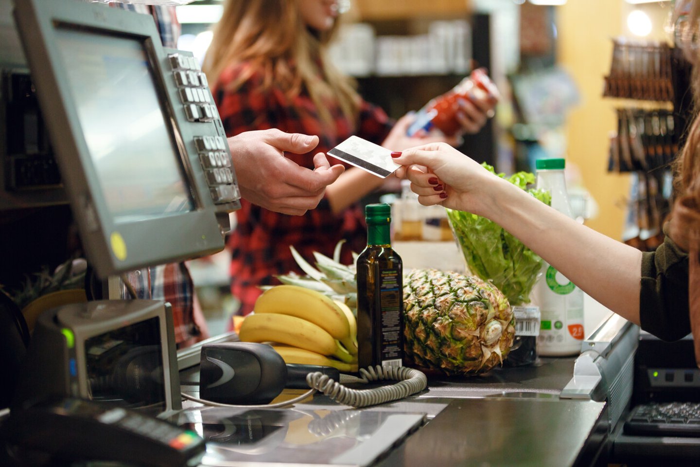 Cropped picture of young man gives credit card to cashier lady at workspace in supermarket.; Shutterstock ID 619563194