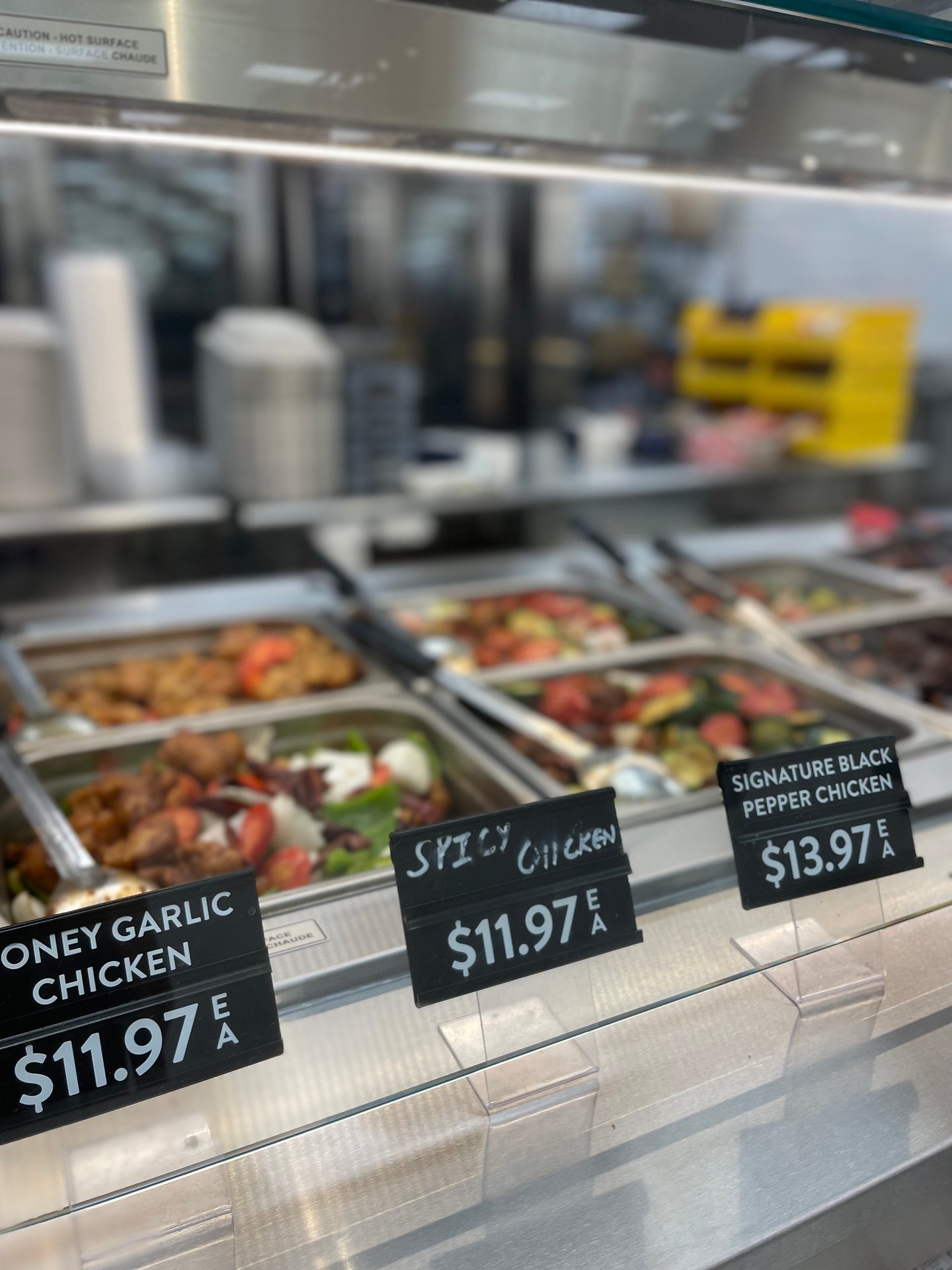 Chicken dishes in metal trays at the Hot Kitchen counter in Walmart's flagship store in Mississauga