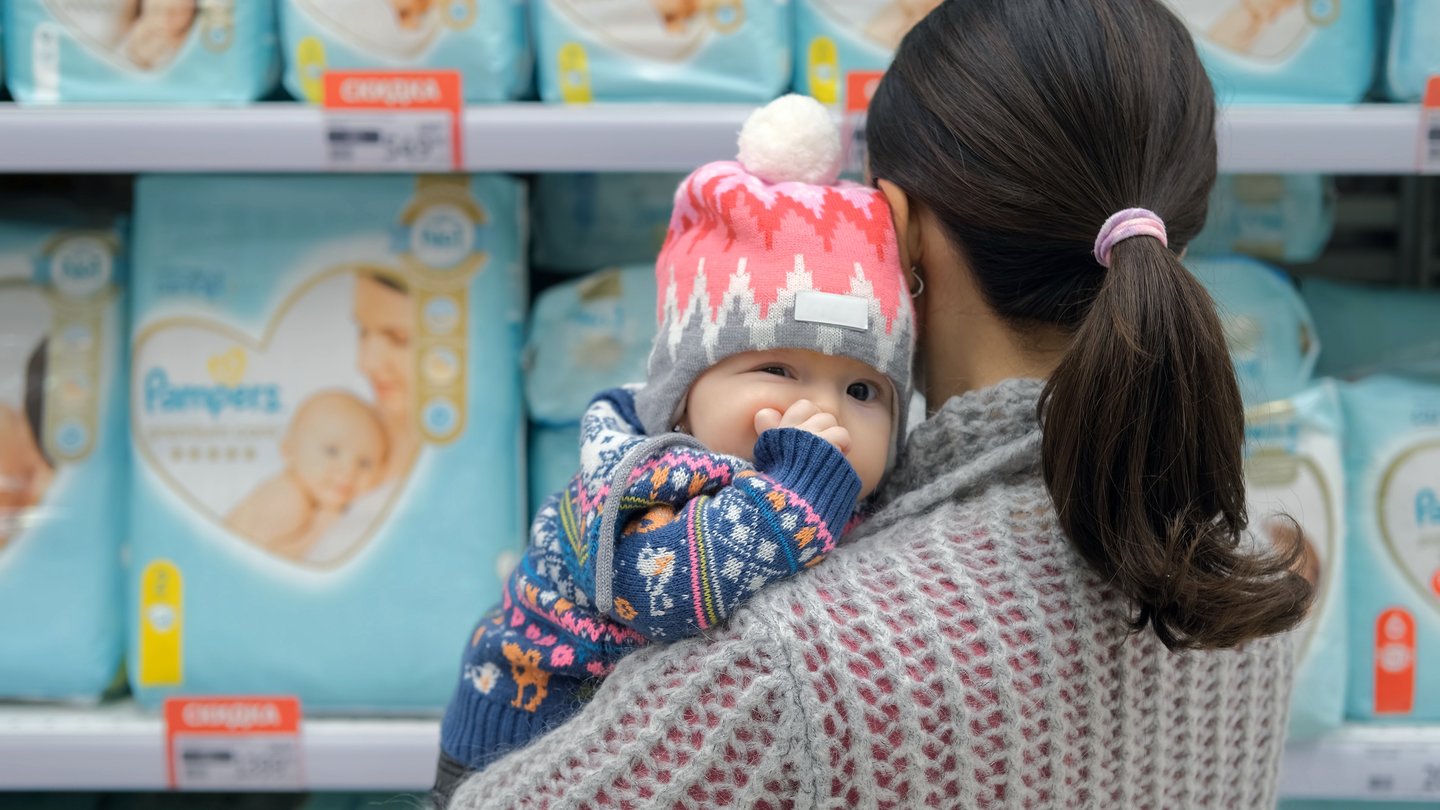 mother buying diapers with baby