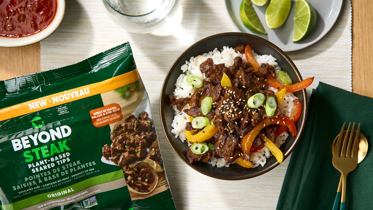 Beyond Steak plant-based protein beef tips on a table next to a bowl of stir fry