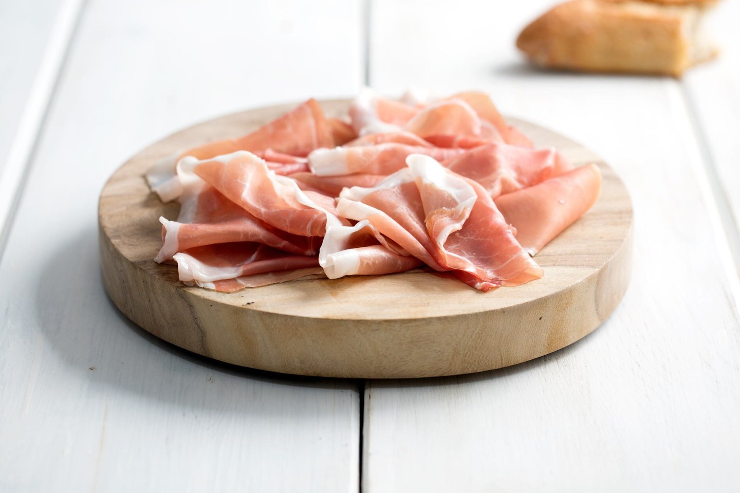 A round wood board with shaved meat on it