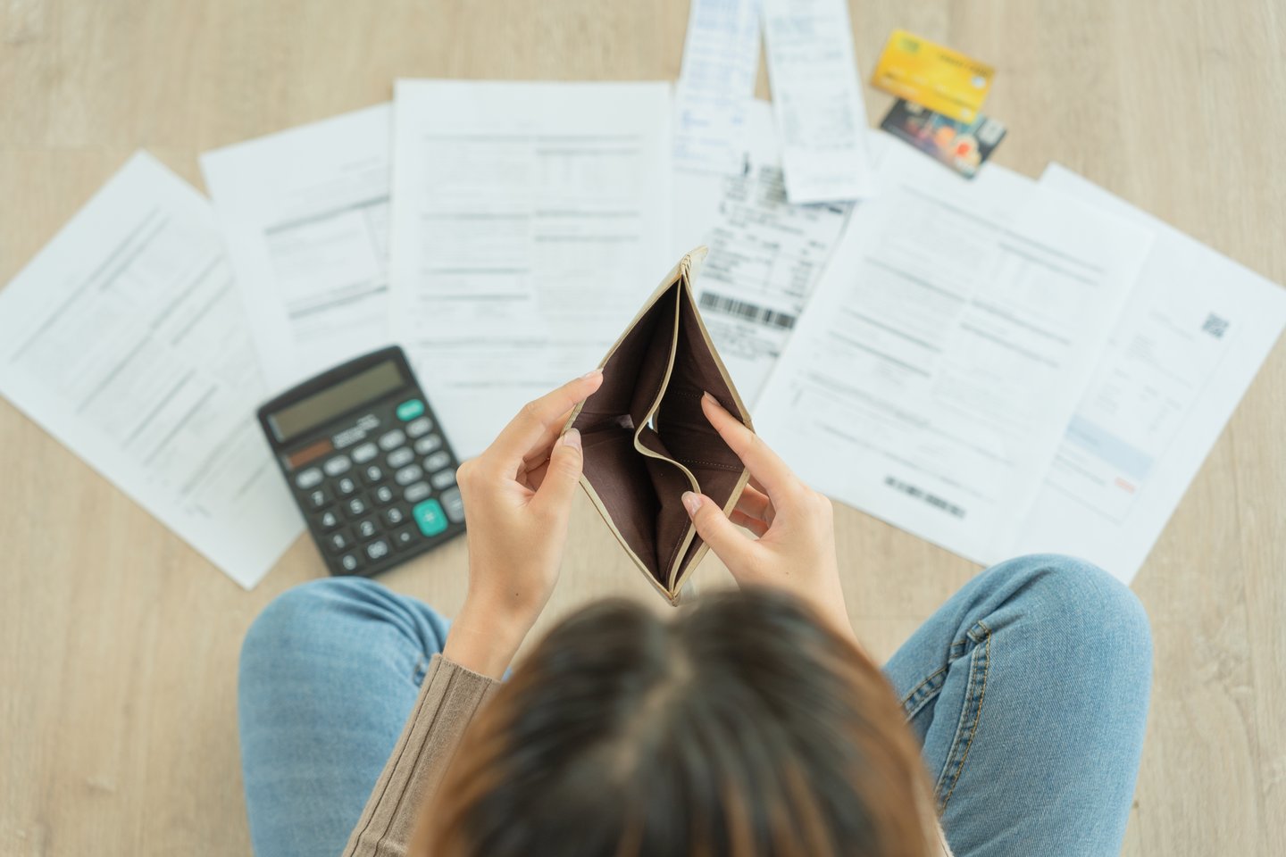 woman looking down at bills with empty wallet