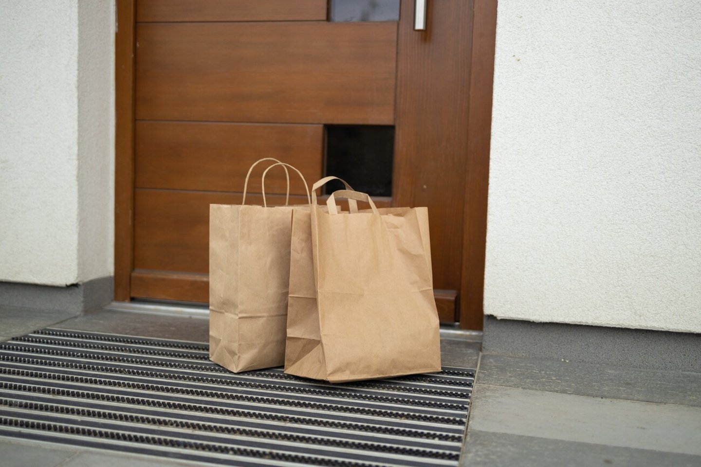 Paper bag with products left by courier of food delivery service during corona virus spreading at front door home; Shutterstock ID 2153403995