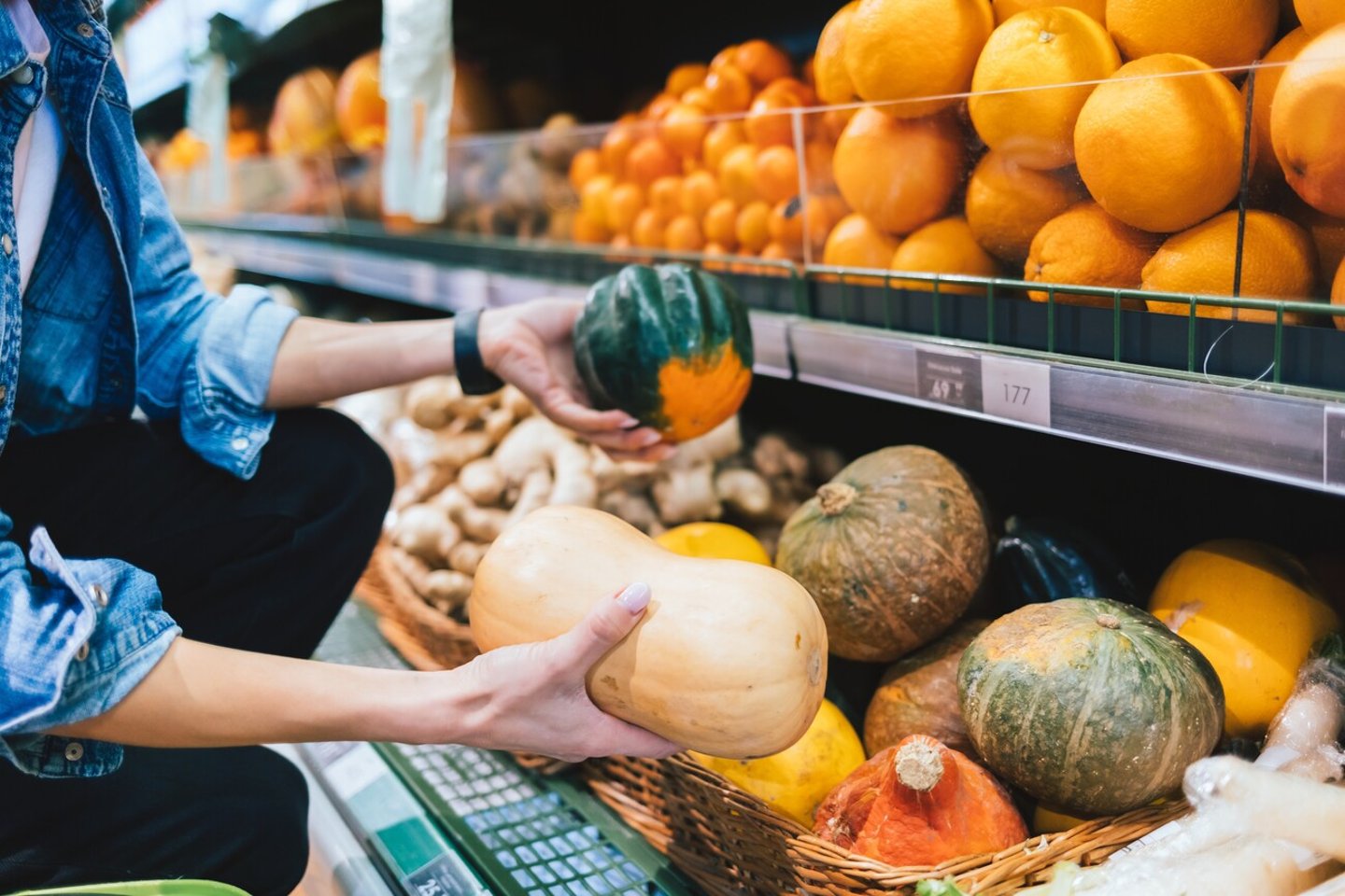 Unrecognizable girl choosing pumpkin in supermarket near shelf with organic fruits and vegetables, close-up; Shutterstock ID 2163652135