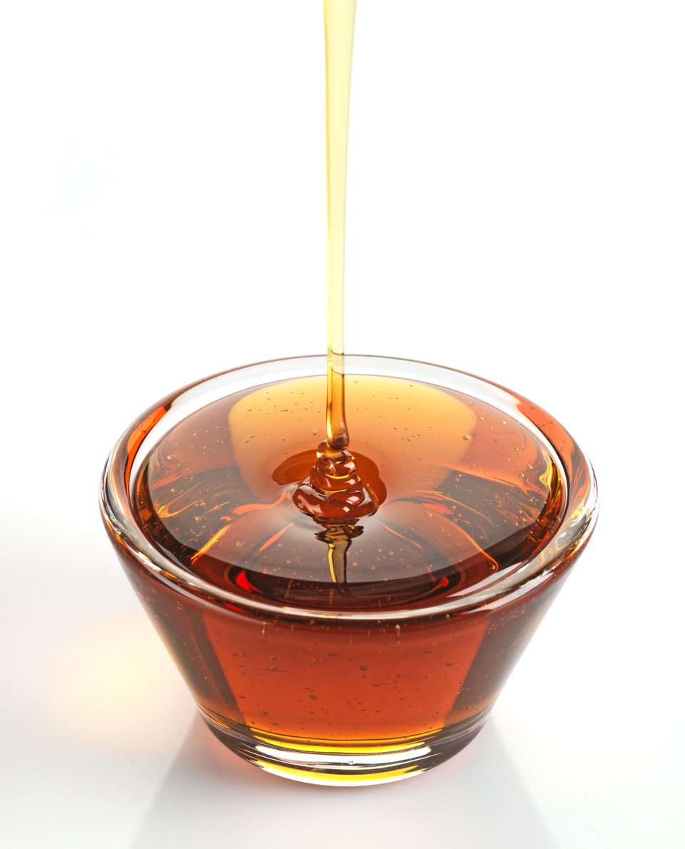 Maple syrup in a bowl on white background