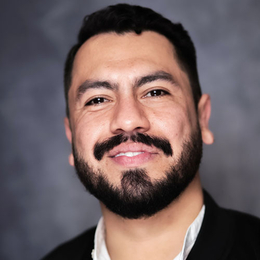 Juan Chacon, a man with dark hair and beard, smiles at the camera