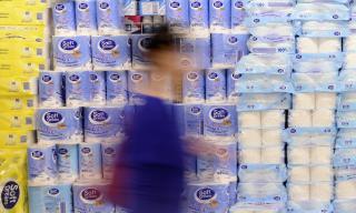 A grocery shoppers walks by a display of toilet paper
