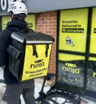 Ninja delivery person on a bike with a branded cooler bag