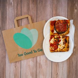 Good To Go brown paper bag next to squares of pizza