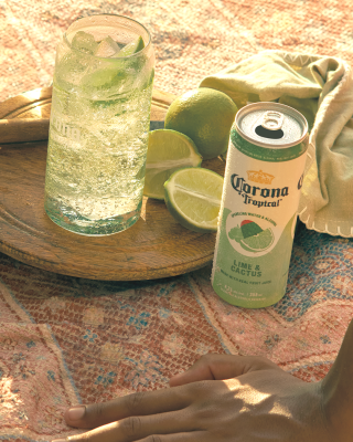 A glass of Corona Tropical on a wood board with lime wedges
