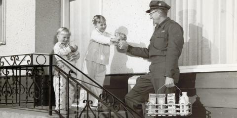 A delivery man drops off boxes of juice to two children