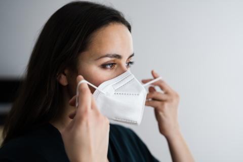 A woman putting on an N-95 mask