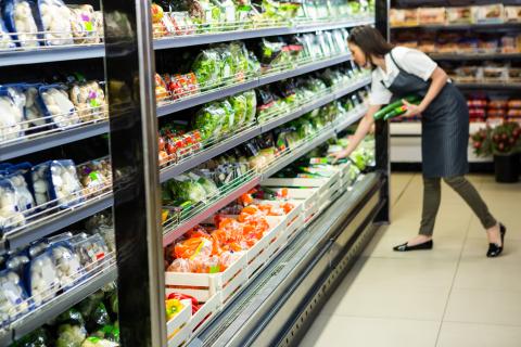 Female grocery store clerk stocking produce
