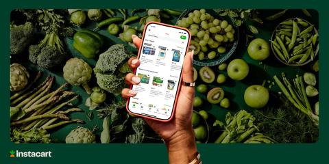 A hand holding up a cellphone against a backdrop of green vegetables with the Instacart app open
