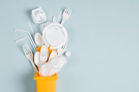 White single use plastic in garbage bin on blue background. Concept of Recycling plastic. Flat lay, top view