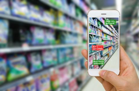 A hand holding a smartphone in a grocery aisle