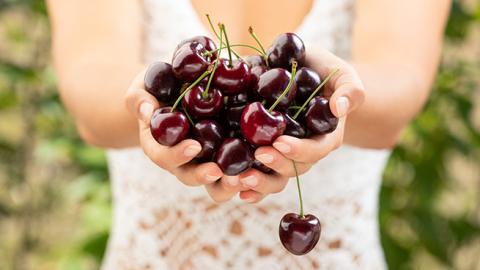 A woman in a white dress holding a handful of cherries