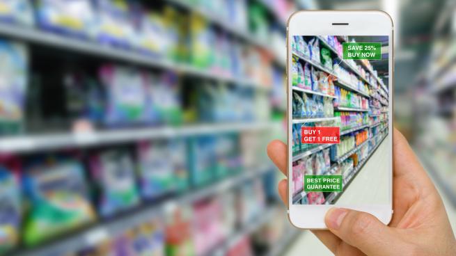 A hand holding a smartphone in a grocery aisle