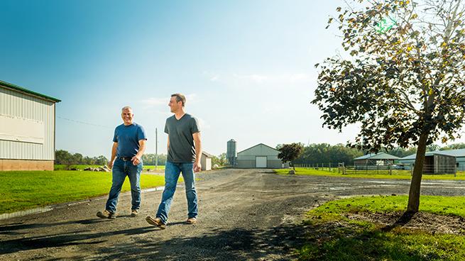 Two farmers walking outside beside a barn