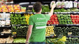 An Instacart shopper picking products from the produce section in a grocery store