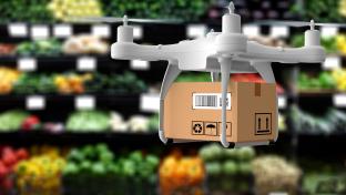 Drone holding a cardboard box hovering in a produce department